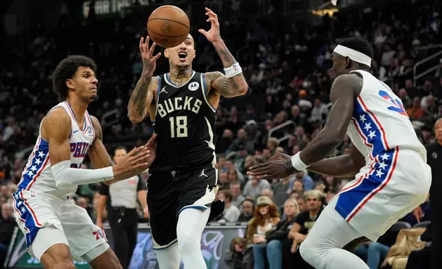 Milwaukee Bucks' Kyle Kuzma (18) controls the ball as he drives to the basket between Philadelphia 76ers' Dominick Barlow, left, and Adem Bona during the first half of an NBA basketball game, Friday, Dec. 5, 2025, in Milwaukee. (AP Photo/Aaron Gash)