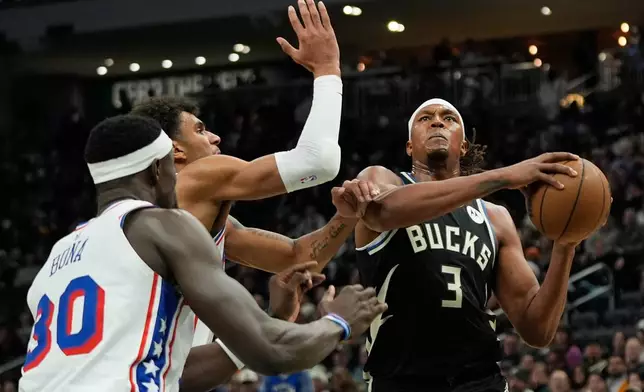 Milwaukee Bucks' Myles Turner (3) drives to the basket against Philadelphia 76ers' Adem Bona (30) and Dominick Barlow during the first half of an NBA basketball game, Friday, Dec. 5, 2025, in Milwaukee. (AP Photo/Aaron Gash)