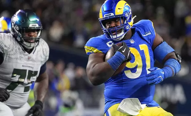 Los Angeles Rams defensive end Kobie Turner runs after making an interception during the second half of an NFL football game against the Seattle Seahawks, Thursday, Dec. 18, 2025, in Seattle. (AP Photo/Lindsey Wasson)