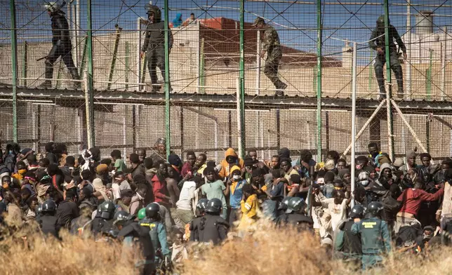 FILE - Riot police officers cordon off the area after migrants arrive on Spanish soil and crossing the fences separating the Spanish enclave of Melilla from Morocco in Melilla, Spain, on June 24, 2022. (AP Photo/Javier Bernardo, File)