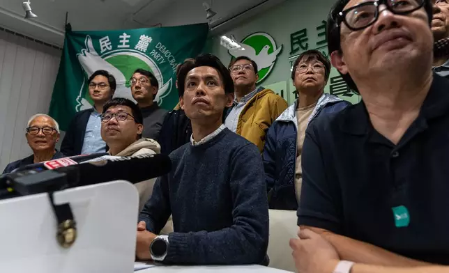 Lo Kin-hei, chairman of Hong Kong's Democratic Party, center, and other committees members pose for photographs at a press conference at the office of Hong Kong's Democratic Party in Hong Kong on Sunday, Dec. 14, 2025. (AP Photo/Chan Long Hei)