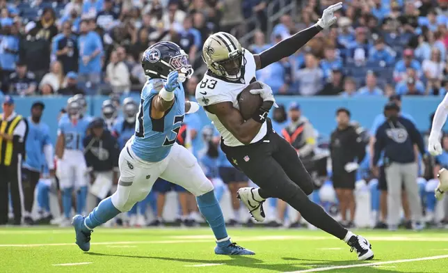 New Orleans Saints tight end Juwan Johnson (83) pulls in a first down reception against Tennessee Titans linebacker Cedric Gray (33) in the second half of an NFL football game, Sunday, Dec. 28, 2025, in Nashville, Tenn. (AP Photo/John Amis)