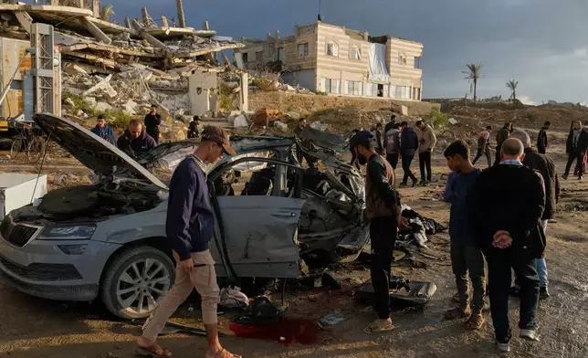 Palestinians looks at a destroyed car following an Israeli strike in Gaza City, Saturday, Dec. 13, 2025. (AP Photo/Jehad Alshrafi)