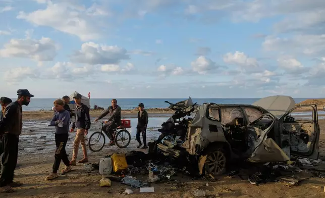 Palestinians looks at a destroyed car following an Israeli strike in Gaza City, Saturday, Dec. 13, 2025. (AP Photo/Jehad Alshrafi)