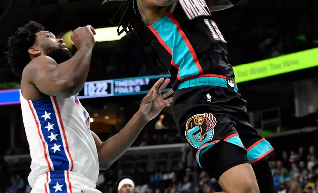 Memphis Grizzlies guard Ja Morant (12) jumps to shoot ahead of Philadelphia 76ers center Joel Embiid (21) in the first half of an NBA basketball game Tuesday, Dec. 30, 2025, in Memphis, Tenn. (AP Photo/Brandon Dill)