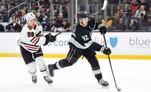 Los Angeles Kings defenseman Brandt Clarke (92) takes a shot and scores as Chicago Blackhawks center Connor Bedard (98) trails behind during the second period of an NHL hockey game Saturday, Dec. 6, 2025, in Los Angeles. (AP Photo/Caroline Brehman)