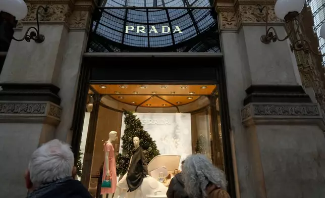 Customers look at a Prada shop window, in Milan, Italy, Tuesday, Dec. 2, 2025. (AP Photo/Luca Bruno)