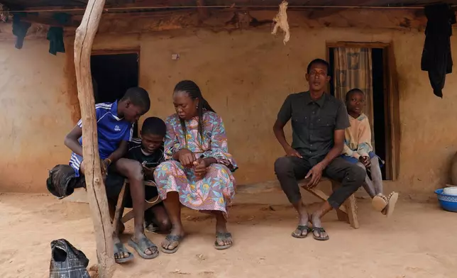 Precious Njikonye, centre, the mother of a student at St. Mary's Catholic School, who was abducted by gunmen and later released, sits outside her house in Papiri, Nigeria, Wednesday, Dec. 10, 2025. (AP Photo/Afolabi Sotunde)
