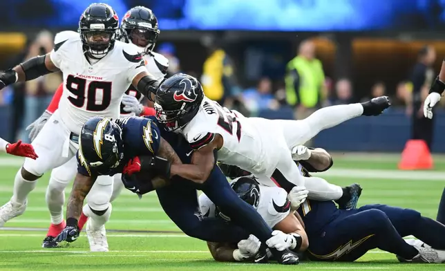 Los Angeles Chargers running back Omarion Hampton (8) is stopped by Houston Texans defensive end Danielle Hunter (55) during the first half of an NFL football game Saturday, Dec. 27, 2025, in Inglewood, Calif. (AP Photo/Wally Skalij)