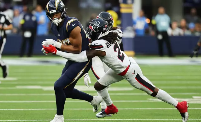 Los Angeles Chargers tight end Oronde Gadsden (86) is grabbed by Houston Texans safety Calen Bullock (2) during the second half of an NFL football game Saturday, Dec. 27, 2025, in Inglewood, Calif. (AP Photo/Kevork Djansezian)