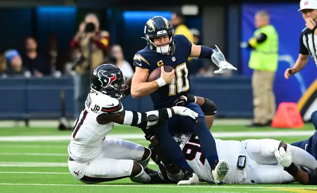 Los Angeles Chargers quarterback Justin Herbert (10) is sacked by Houston Texans defensive end Will Anderson Jr. (51) during the first half of an NFL football game Saturday, Dec. 27, 2025, in Inglewood, Calif. (AP Photo/Wally Skalij)