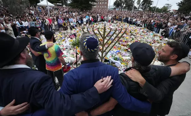 Mourners gather at a menorah lighting ceremony at a floral memorial for victims of Sunday's shooting, at the Bondi Pavilion at Bondi Beach on Tuesday, Dec. 16, 2025, in Sydney, Australia. (AP Photo/Mark Baker)