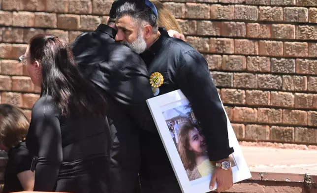 A man carries a photo of Bondi Beach mass shooting victim 10-year-old Matilda, whose last name is being withheld at the request of her family, at her funeral in Sydney, Thursday, Dec. 18, 2025. (AP Photo/Steve Markham)