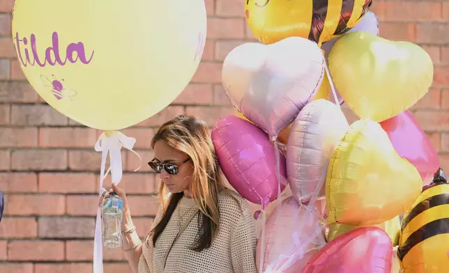 A woman carries balloons to the funeral of Bondi Beach mass shooting victim 10-year-old Matilda, whose last name is being withheld at the request of her family, in Sydney, Thursday, Dec. 18, 2025. (AP Photo/Steve Markham)