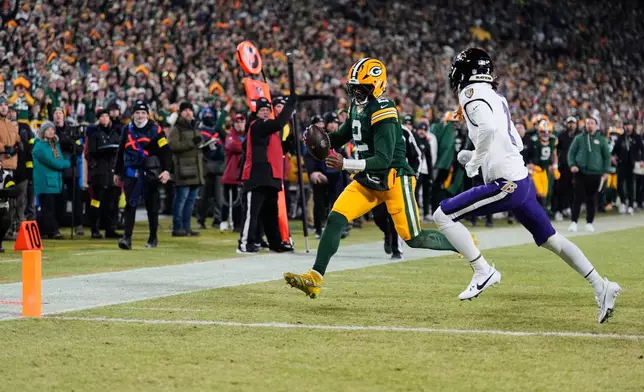 Green Bay Packers quarterback Malik Willis, left, runs toward the end zone to score a touchdown past Baltimore Ravens cornerback Nate Wiggins, right, during the second half of an NFL football game, Saturday, Dec. 27, 2025, in Green Bay, Wis. (AP Photo/Morry Gash)