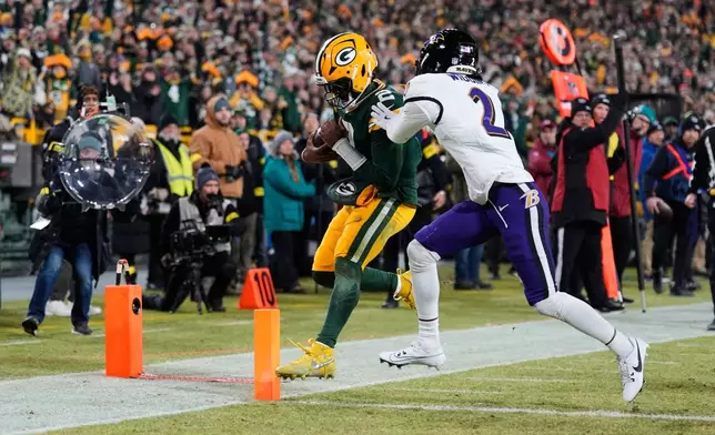 Green Bay Packers quarterback Malik Willis, left, runs toward the end zone to score a touchdown past Baltimore Ravens cornerback Nate Wiggins, right, during the second half of an NFL football game, Saturday, Dec. 27, 2025, in Green Bay, Wis. (AP Photo/Morry Gash)