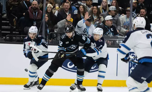 Utah Mammoth center Kevin Stenlund (82) fights for the puck against Winnipeg Jets center Cole Perfetti (91) and center Vladislav Namestnikov (7) during the first period of an NHL hockey game Sunday, Dec. 21, 2025, in Salt Lake City. (AP Photo/Melissa Majchrzak)