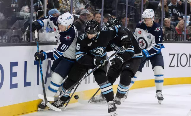 Winnipeg Jets center Cole Perfetti (91) fights for the puck against Utah Mammoth defenseman John Marino (6) during the second period of an NHL hockey game Sunday, Dec. 21, 2025, in Salt Lake City. (AP Photo/Melissa Majchrzak)