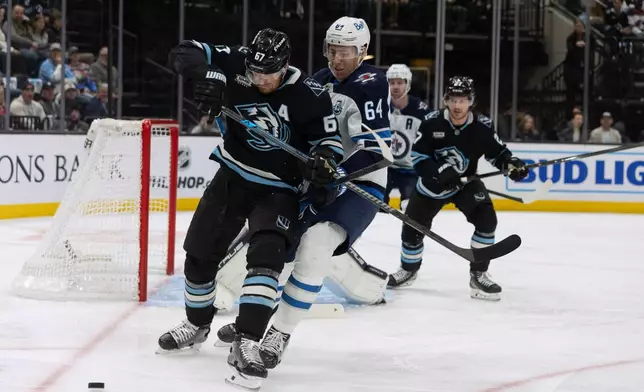 Utah Mammoth left wing Lawson Crouse, front, fights for the puck against Winnipeg Jets defenseman Logan Stanley (64) during the first period of an NHL hockey game, Sunday, Dec. 21, 2025, in Salt Lake City. (AP Photo/Melissa Majchrzak)