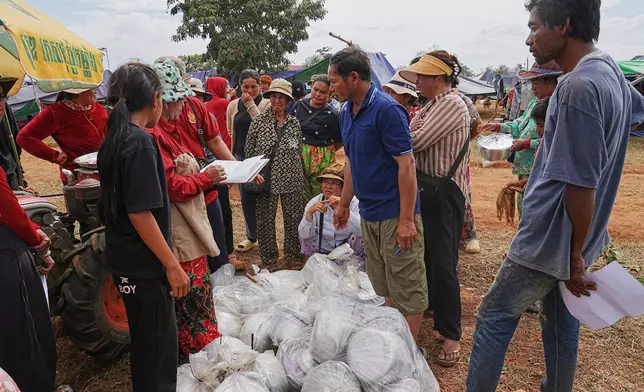 Evacuees wait for receiving a pot to cook rice as they take refuge at Chonkal in Oddar Meanchey province, Cambodia Thursday, Dec. 11, 2025, after fleeing homes following a fighting between Thailand and Cambodia over territorial claims. (AP Photo/Heng Sinith)