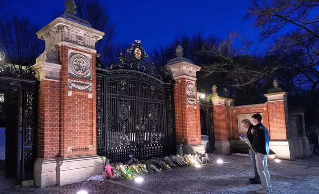Visitors pause at a makeshift memorial for the victims of Saturday's shooting, at the Van Wickle Gate at Brown University, Monday, Dec. 15, 2025, in Providence, R.I.(AP Photo/Robert F. Bukaty)