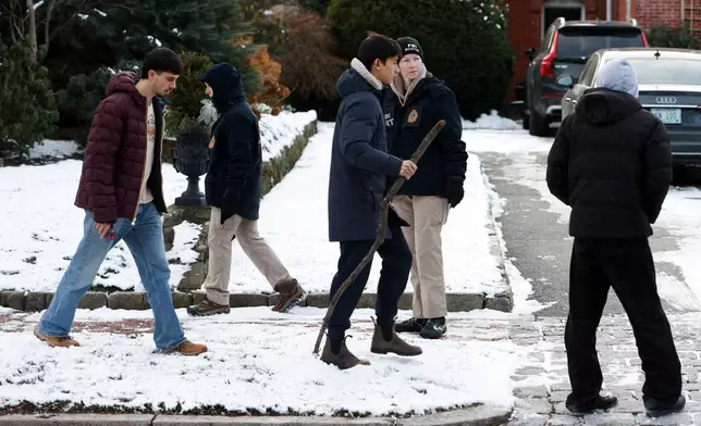 Pedestrians ask FBI agents, on the sidewalk on Cooke St. for updates, in Providence, R.I., two days after a shooting occurred on Brown University's campus, Monday, Dec. 15, 2025. (Lily Speredelozzi/The Sun Chronicle via AP)