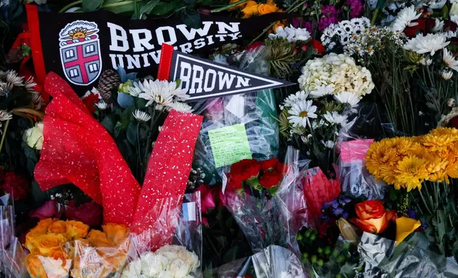 Community flowers, notes and mementos are placed in a makeshift memorial display in front of Brown University's Van Wickle gates, in Providence, R.I., two days after a shooting took place on Brown University's campus, Monday, Dec. 15, 2025. (Lily Speredelozzi/The Sun Chronicle via AP)