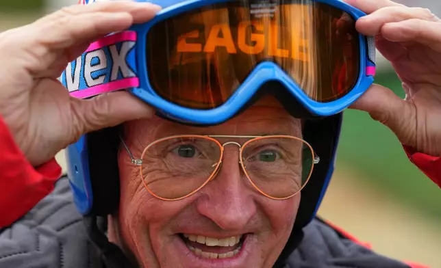 British former ski jumper Michael Edwards, known as Eddie the Eagle, wears a replica of his 1988 helmet with the original glasses during an interview at the Ski and Snowboard Center, in Gloucester, England, Wednesday, Nov. 19, 2025. (AP Photo/Frank Augstein)