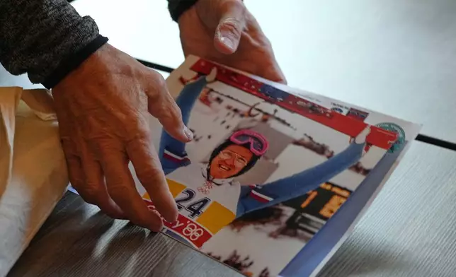 British former ski jumper Michael Edwards, known as Eddie the Eagle, arranges his photos from the 1988 Winter Olympics in Calgary, during an interview at the Ski and Snowboard Center, in Gloucester, England, Wednesday, Nov. 19, 2025. (AP Photo/Frank Augstein)