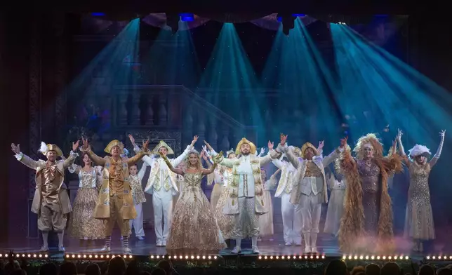 Michael Edwards, better known as Eddie the Eagle, left, playing Professor Crackpot, receives applaud as he performs with fellow actors in the pantomime "Beauty and the Beast" at Watersmeet Theatre in Rickmansworth, England, Dec. 5 2025. (AP Photo/Thomas Krych)