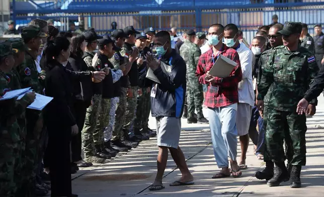 In this photo released by Agence Kampuchea Press (AKP), Cambodian soldiers, center, arrive after being captured and held by the Thai army, at Prum border gate, in Pailin province, Cambodia, Wednesday, Dec. 31, 2025. (AKP via AP)