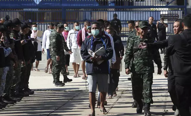 In this photo released by Agence Kampuchea Press (AKP), Cambodian soldiers, center, arrive after being captured and held by the Thai army, at Prum border gate, in Pailin province, Cambodia, Wednesday, Dec. 31, 2025. (AKP via AP)