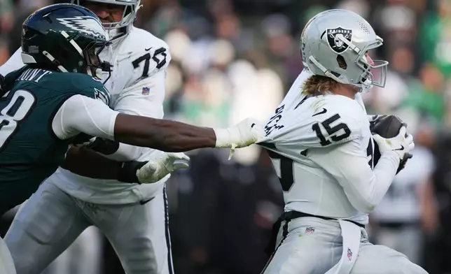 Philadelphia Eagles linebacker Jalyx Hunt (58) grabs Las Vegas Raiders quarterback Kenny Pickett (15) during the second half of an NFL football game Sunday, Dec. 14, 2025, in Philadelphia. (AP Photo/Matt Slocum)