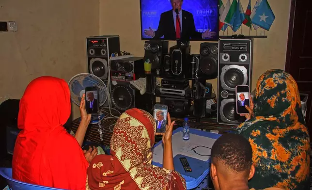 A Somali family watches a speech by U.S. president Donald Trump on their phones and on television, in Mogadishu, Somalia, Wednesday, Dec. 3, 2025. (AP Photo/Farah Abdi Warsameh)