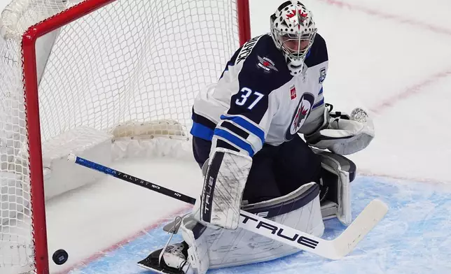 Winnipeg Jets goaltender Connor Hellebuyck allows a shot by Colorado Avalanche defenseman Brent Burns to go into the net for a goal in the first period of an NHL hockey game Friday, Dec. 19, 2025, in Denver. (AP Photo/David Zalubowski)
