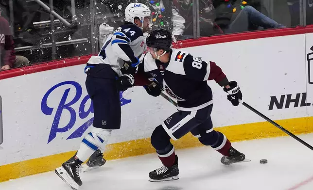 Colorado Avalanche center Martin Necas, right, checks Winnipeg Jets defenseman Josh Morrissey, left, in the first period of an NHL hockey game Friday, Dec. 19, 2025, in Denver. (AP Photo/David Zalubowski)