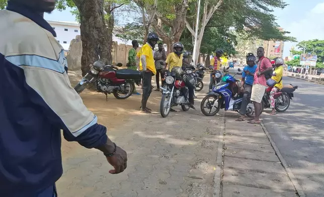People gather near a roadway amid an attempted coup in Cotonou, Benin, Sunday Dec. 7, 2025. (AP Photo)