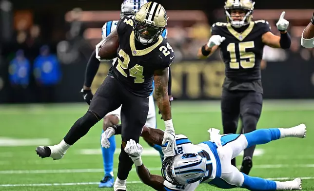 New Orleans Saints safety Terrell Burgess (24) runs the ball against Carolina Panthers safety Nick Scott (21) in the first half of an NFL football game Sunday, Dec. 14, 2025, in New Orleans. (AP Photo/Ella Hall)