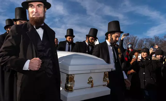 Men dressed as former President Abraham Lincoln carry a casket down the steps in front of the Lincoln Memorial during a mock funeral for the penny, which was discontinued earlier this year, Saturday, Dec. 20, 2025, in Washington. (AP Photo/Julia Demaree Nikhinson)