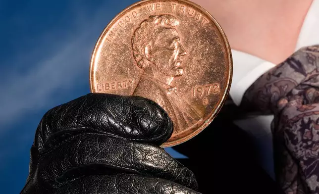 A person holds a giant penny at a mock funeral for the coin, which was discontinued earlier this year, Saturday, Dec. 20, 2025, in front of the Lincoln Memorial in Washington. (AP Photo/Julia Demaree Nikhinson)