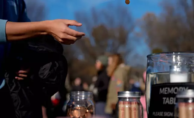 A person tosses a penny into a jar during a mock funeral for the penny, which was discontinued earlier this year, Saturday, Dec. 20, 2025, in front of the Lincoln Memorial in Washington. (AP Photo/Julia Demaree Nikhinson)