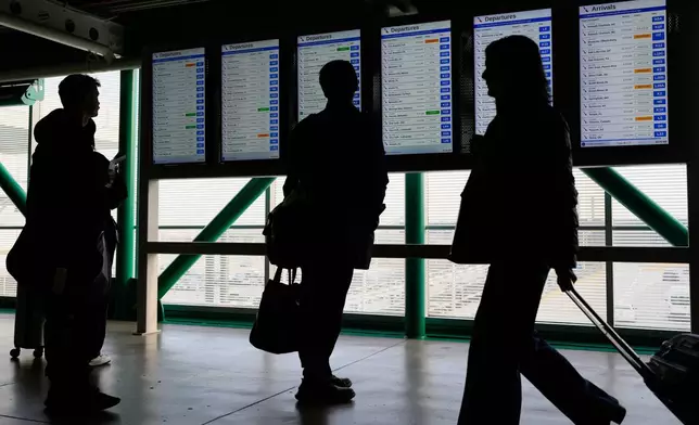 Travelers check their flight times on a information screen at O'Hare airport in Chicago, Tuesday, Dec. 23, 2025. (AP Photo/Nam Y. Huh)
