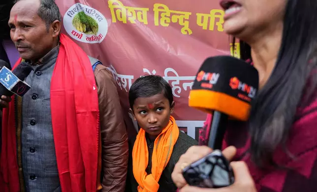 A boys looks at a journalist covering a protest by Vishwa Hindu Parishad, a prominent right-wing Hindu nationalist organization, accusing Bangladeshi groups of wrongly targeting Indians, in New Delhi, India, Tuesday, Dec. 23, 2025. (AP Photo/Manish Swarup)