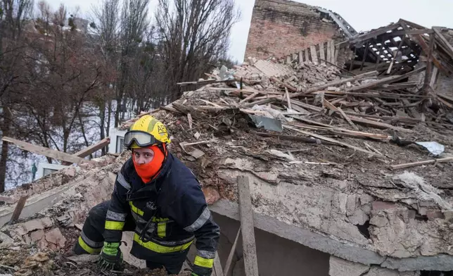 A rescue worker climbs onto the roof of apartment building damaged after a Russian strike on Kyiv, Ukraine, on Saturday, Dec. 27, 2025. (AP Photo/Evgeniy Maloletka)