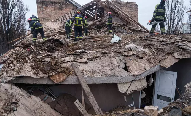 Rescue workers clear the rubble at the roof of apartment building damaged after a Russian strike on Kyiv, Ukraine, on Saturday, Dec. 27, 2025. (AP Photo/Evgeniy Maloletka)