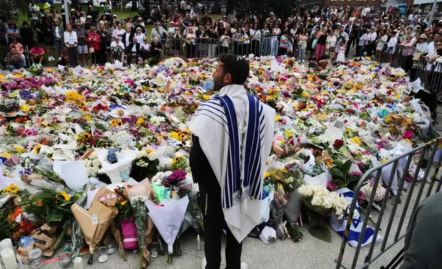 Rabbi Yossi Friedman speaks to people gathering at a flower memorial by the Bondi Pavilion at Bondi Beach on Tuesday, Dec. 16, 2025, following Sunday's shooting in Sydney, Australia. (AP Photo/Mark Baker)
