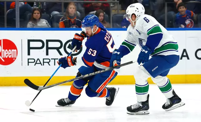 New York Islanders center Casey Cizikas (53) plays the puck against Vancouver Canucks right wing Brock Boeser (6) during the second period of an NHL hockey game, Friday, Dec. 19, 2025, in Elmont, NY. (AP Photo/Noah K. Murray)