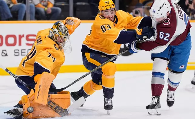 Colorado Avalanche left wing Artturi Lehkonen (62) scores a goal past Nashville Predators goaltender Juuse Saros (74) and defenseman Adam Wilsby (83) during the first period of an NHL hockey game Tuesday, Dec. 9, 2025, in Nashville, Tenn. (AP Photo/George Walker IV)