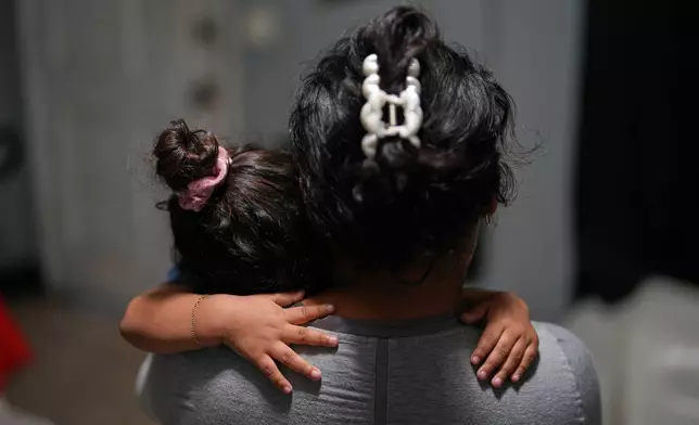 Pregnant asylum-seeker Yaoska, 32, comforts her two-year-old son who was not feeling well, inside the Miami-area motel room where she and her children are living after her husband was deported to Nicaragua, Thursday, Nov. 13, 2025. (AP Photo/Rebecca Blackwell)
