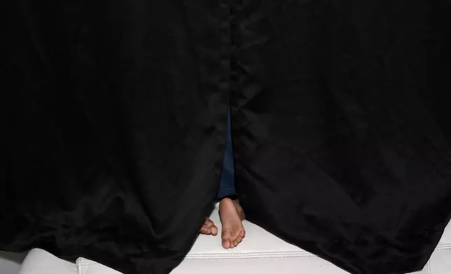 The two-year-old son of pregnant, asylum-seeker Yaoska peers out the window of the Miami-area motel room where he lives with his mother and brother, after their father was deported to Nicaragua, Thursday, Nov. 13, 2025. (AP Photo/Rebecca Blackwell)